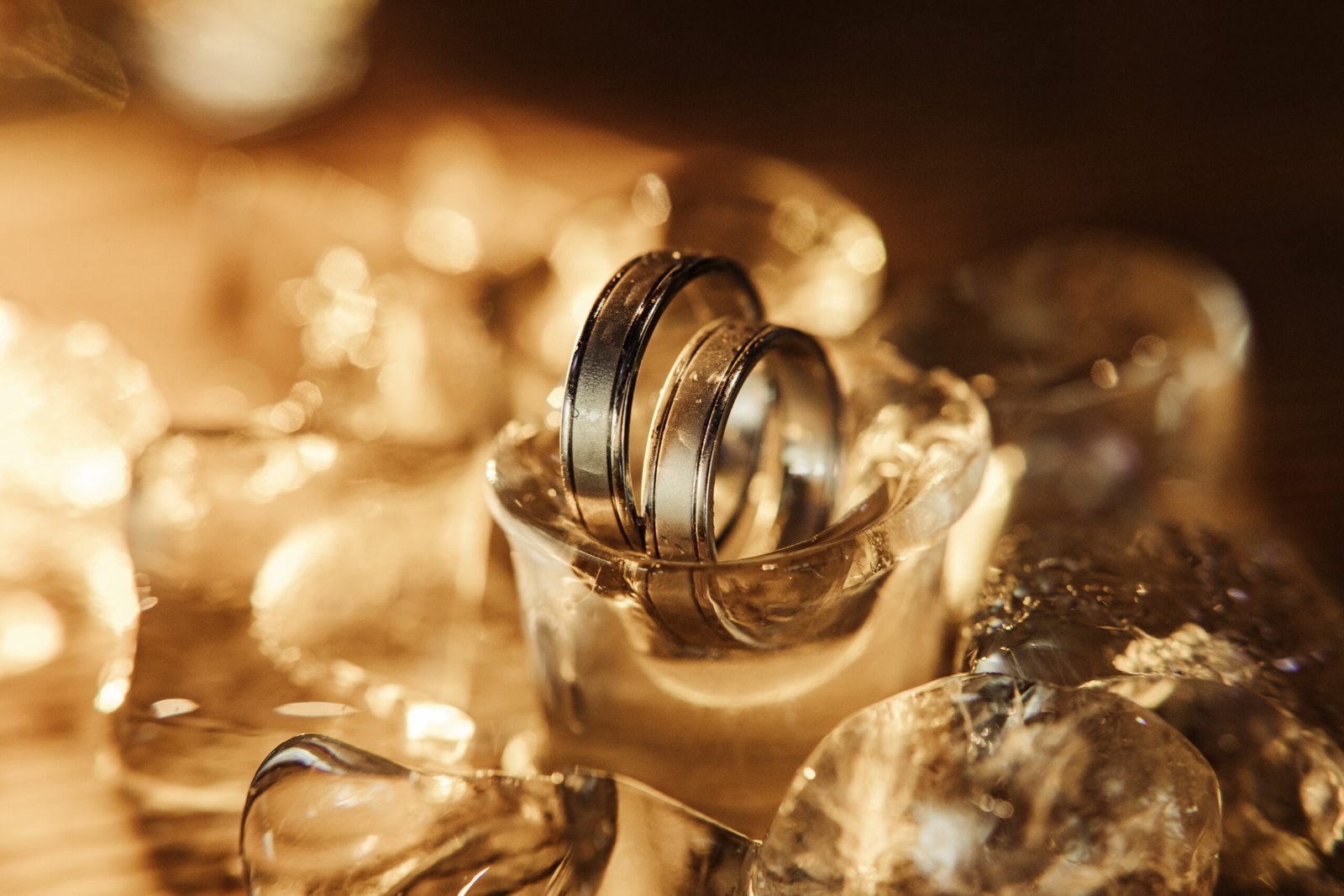 pair of gold wedding rings on ice cubes sparkle and reflection